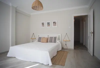 a white bedroom with a white bed and a hallway at Playa Victoria Ha Apartment in Cádiz