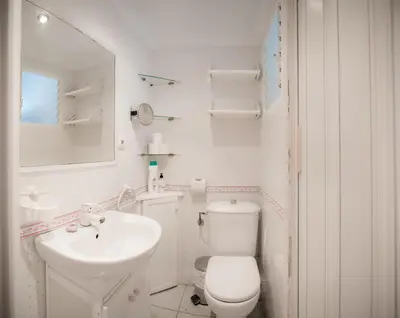 a white bathroom with a toilet and a sink at Playa Victoria Ha Apartment in Cádiz