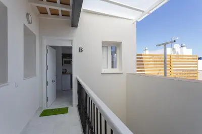 a white house with a hallway and a balcony at Apartamentos La BRUJULA by CadizRentals in Cádiz