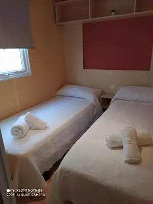 two beds in a room with towels on them at Bungalows Buda Beach in Sanlúcar de Barrameda