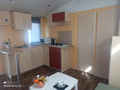 a small kitchen with wooden cabinets and a table at Bungalows Buda Beach in Sanlúcar de Barrameda
