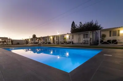 a swimming pool in front of a house at Bungalows Buda Beach in Sanlúcar de Barrameda
