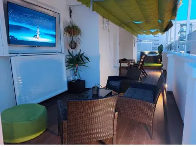 a living room with chairs and a tv on the wall at ÁTICO VICTORIA BEACH in Cádiz