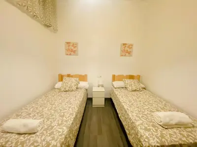 two beds in a room with white walls and wooden floors at La Posada de Sacramento Grupo AC Gestion in Cádiz