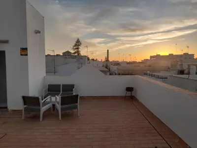 a balcony with two chairs and a table on a building at El Sardinero in Chipiona