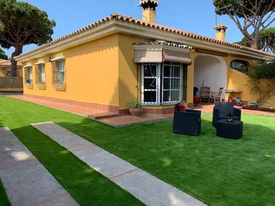 a yellow house with a lawn in front of it at Chiclana casa maría in Chiclana de la Frontera