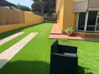 a green lawn with a bench in a yard at Chiclana casa maría in Chiclana de la Frontera