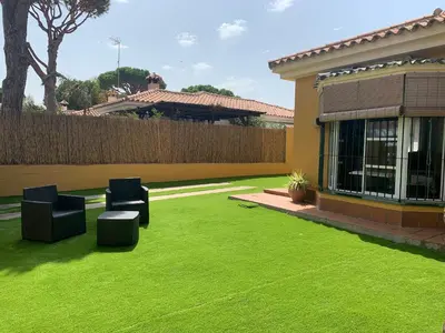 a yard with green grass and two chairs and a house at Chiclana casa maría in Chiclana de la Frontera