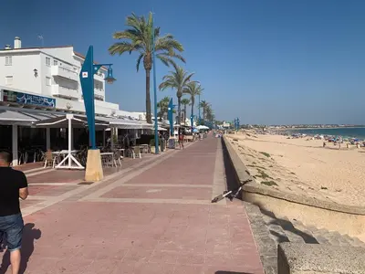 a man walking down a sidewalk next to the beach at Chiclana casa maría in Chiclana de la Frontera