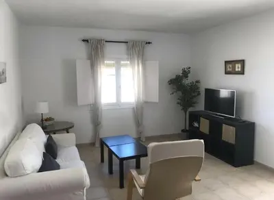 a living room with a white couch and a tv at Bajo con encanto a pie de playa in Chipiona