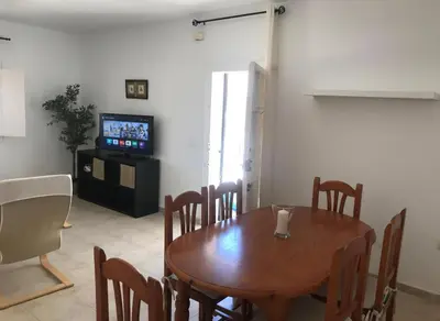 a dining room with a wooden table and a television at Bajo con encanto a pie de playa in Chipiona