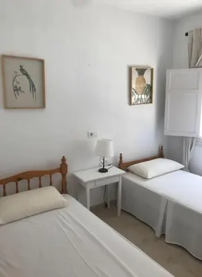 a bedroom with two beds and a table with a lamp at Bajo con encanto a pie de playa in Chipiona