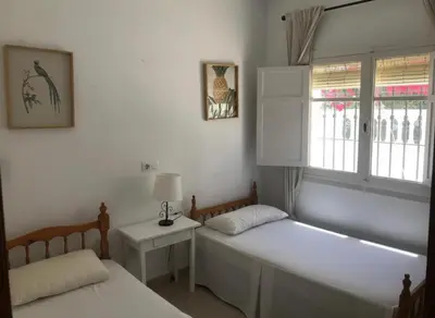 a bedroom with two beds and a window at Bajo con encanto a pie de playa in Chipiona