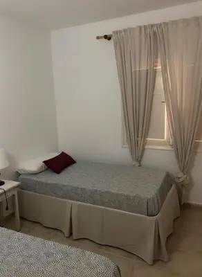 a bedroom with two beds and a window at Bajo con encanto a pie de playa in Chipiona