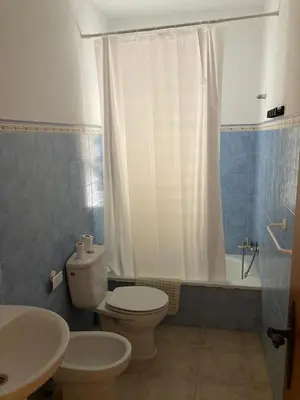 a bathroom with a white toilet and a sink at Bajo con encanto a pie de playa in Chipiona