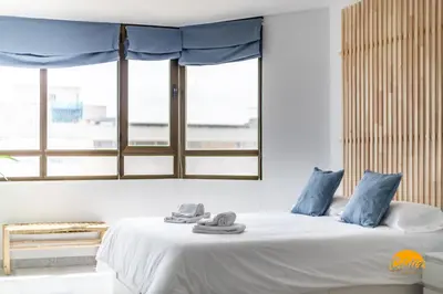 a bedroom with a bed with blue pillows and a window at Loft Victoria Beach - FREE PARKING by Cadiz Time in Cádiz