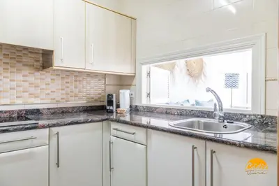 a kitchen with white cabinets and a sink and a window at Loft Victoria Beach - FREE PARKING by Cadiz Time in Cádiz