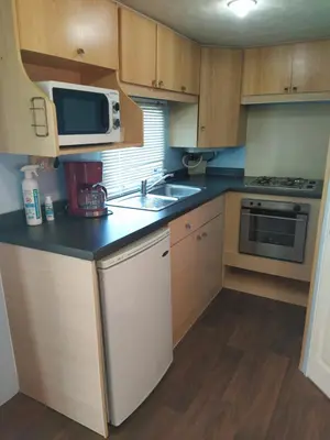 a small kitchen with a sink and a microwave at Residencial Robles in Sanlúcar de Barrameda