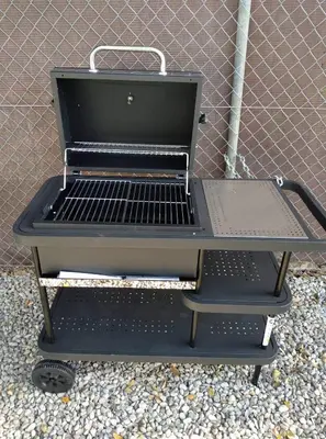 a grill sitting on a stand in front of a fence at Residencial Robles in Sanlúcar de Barrameda