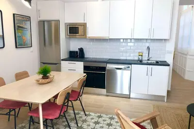 a kitchen with white cabinets and a table with chairs at GATU PREMIUM Villa Libertad in Cádiz