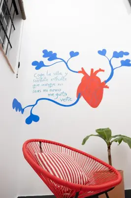 a red chair in front of a wall with a spider on it at Casa Miguel - Apartamento 1 in Sanlúcar de Barrameda