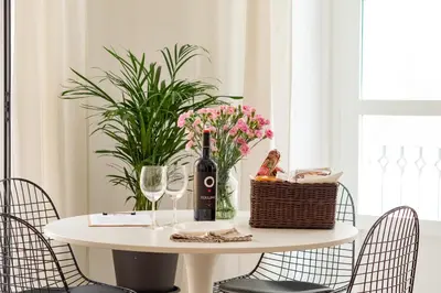 a white table with a bottle of wine and flowers at Casa Miguel - Apartamento 3 in Sanlúcar de Barrameda