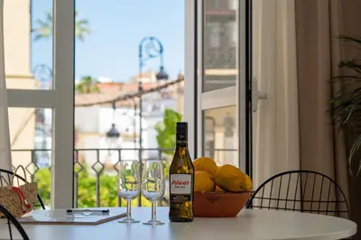 a bottle of wine sitting on a table with glasses at Casa Miguel - Apartamento 3 in Sanlúcar de Barrameda