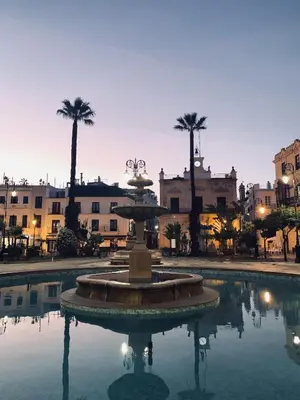 a fountain in the middle of a courtyard with palm trees at Casa Miguel - Apartamento 3 in Sanlúcar de Barrameda