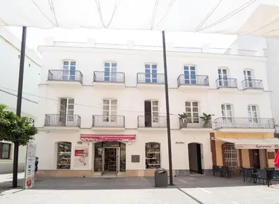 a white building with balconies on a street at Casa Miguel - Apartamento 5 in Sanlúcar de Barrameda