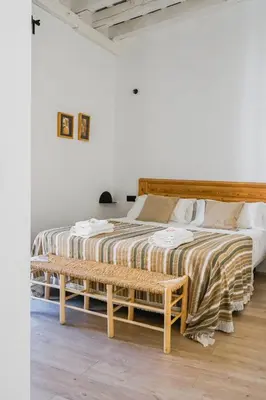 a bedroom with a bed with a bench next to it at Casa Miguel - Apartamento 5 in Sanlúcar de Barrameda