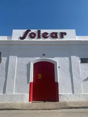 a red door in a white building with a sign at Casa Miguel - Apartamento 6 in Sanlúcar de Barrameda