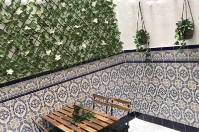 a bench in front of a wall with flowers at El patio de San Isidro by Gades Gestión in Cádiz