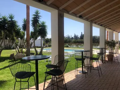 a patio with tables and chairs and palm trees at Hacienda Soto-Hego Haizea in Chiclana de la Frontera