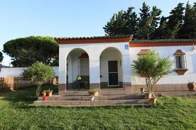 a small white house with a porch and stairs at Chalet con piscina, amplio jardin y aire acondicionado in Chiclana de la Frontera