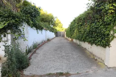 a long alley with a white wall and a gate at Chalet con piscina, amplio jardin y aire acondicionado in Chiclana de la Frontera