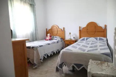 a bedroom with two beds and a teddy bear sitting on it at Chalet con piscina, amplio jardin y aire acondicionado in Chiclana de la Frontera