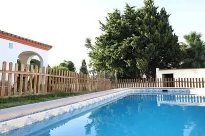 a swimming pool in front of a wooden fence at Chalet con piscina, amplio jardin y aire acondicionado in Chiclana de la Frontera
