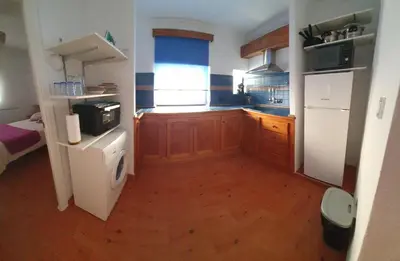 a small kitchen with wooden cabinets and a window at GirasolesV in Sanlúcar de Barrameda