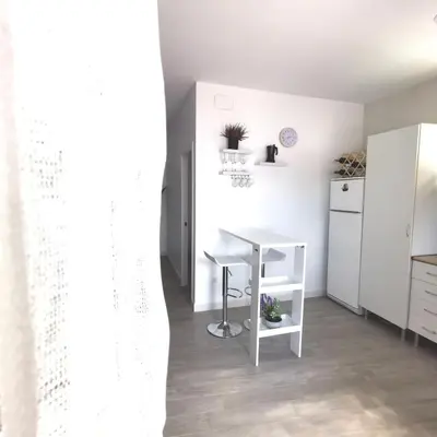 a kitchen with a white table and a white refrigerator at Brisa marina novo sancti petri in Chiclana de la Frontera