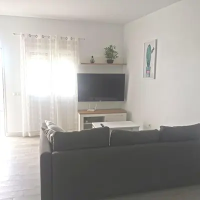 a living room with a couch and a tv at Brisa marina novo sancti petri in Chiclana de la Frontera