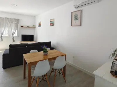 a living room with a wooden table and white chairs at Brisa marina novo sancti petri in Chiclana de la Frontera