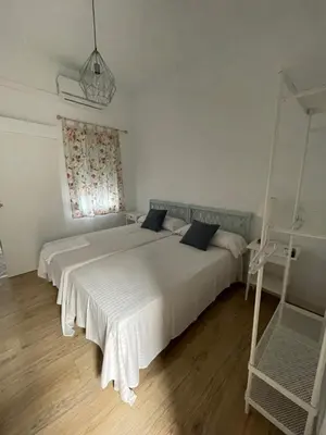 a bedroom with a large white bed and a window at HOSTAL LA CRUZ 1872 in Chipiona