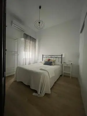 a white bedroom with a large bed and a table at HOSTAL LA CRUZ 1872 in Chipiona