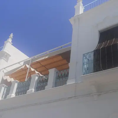 a balcony of a white building with an open window at HOSTAL LA CRUZ 1872 in Chipiona