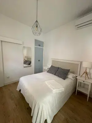 a white bedroom with a large white bed and a lamp at HOSTAL LA CRUZ 1872 in Chipiona
