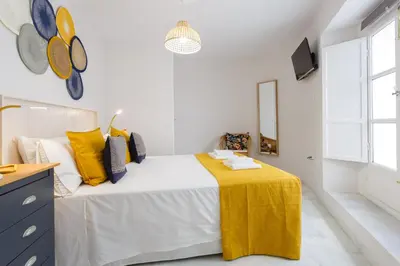 a bedroom with a bed with a yellow blanket on it at Apartamento El NOBLE by Cadiz4Rentals in Cádiz