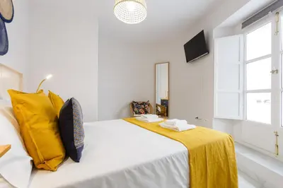 a white bedroom with a bed with yellow pillows at Apartamento El NOBLE by Cadiz4Rentals in Cádiz