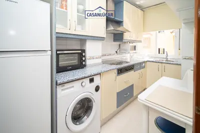 a kitchen with a washing machine and a refrigerator at Piso Nao Victoria in Sanlúcar de Barrameda