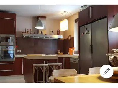 a kitchen with brown cabinets and a table and chairs at habitacion en casa kenya in Jerez de la Frontera