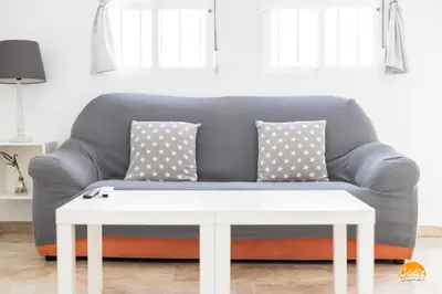 a grey couch with pillows and a white coffee table at Apartamento Encanto Gaditano con Terraza by Cádiz Time in Cádiz